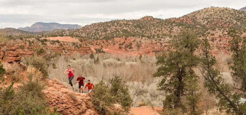 male and female running up canyon in activewear.